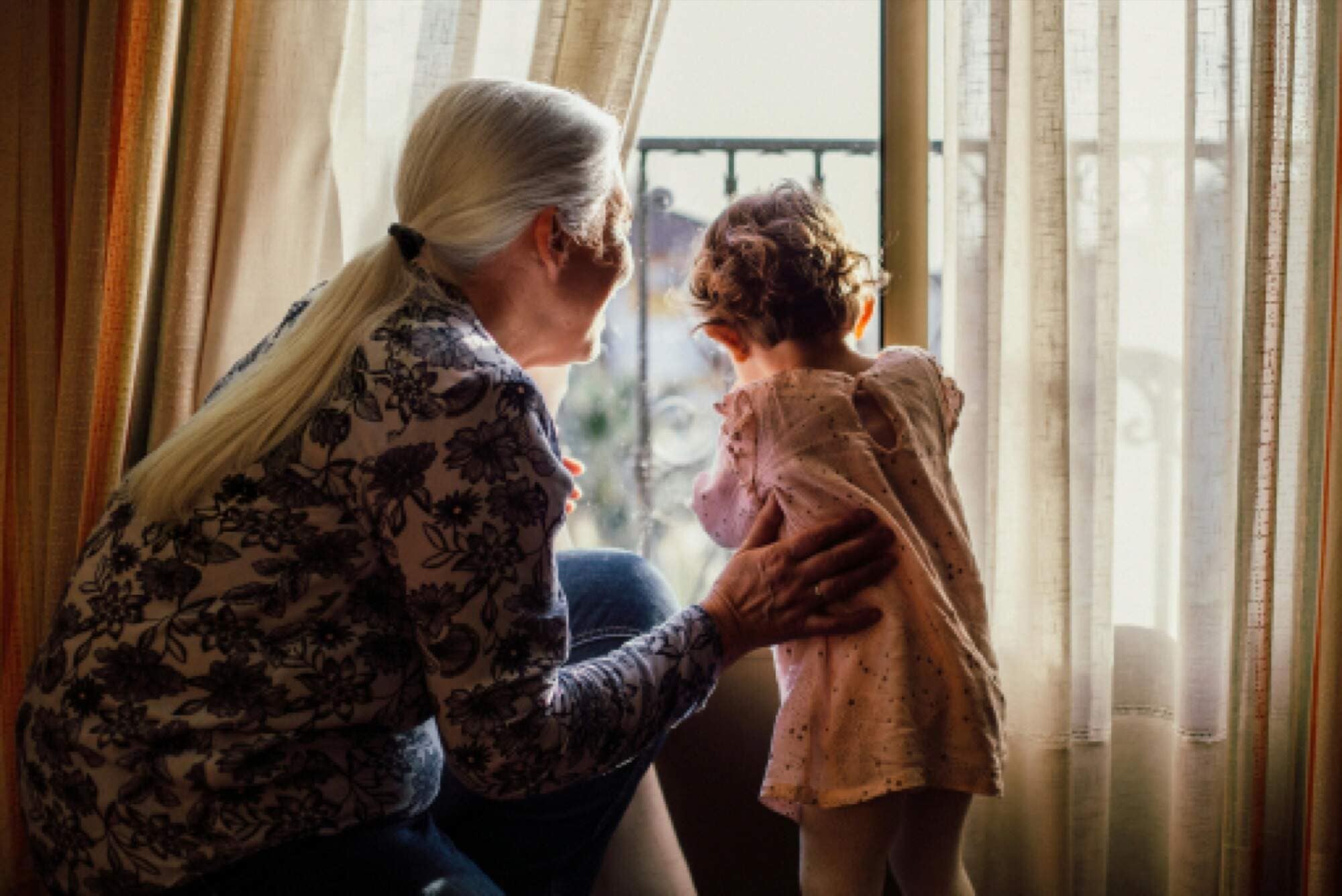A grandmother and child looking out the kitchen window together