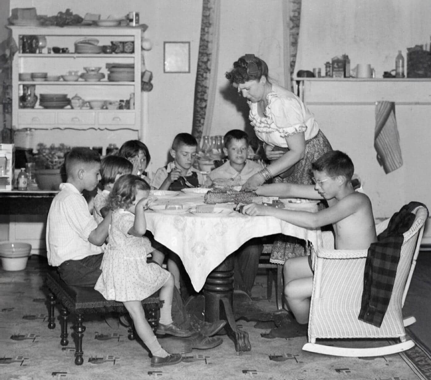 Archival black-and-white photo of a large family gathered around a dinner table