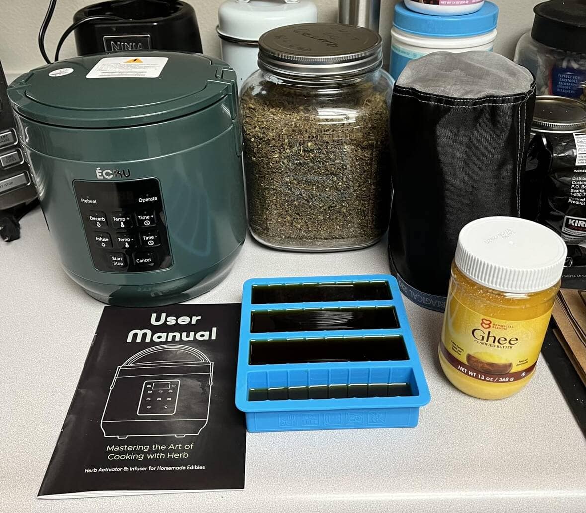 Customer photo: decarboxylator beside a jar of herbs, ghee, silicone molds and the user manual