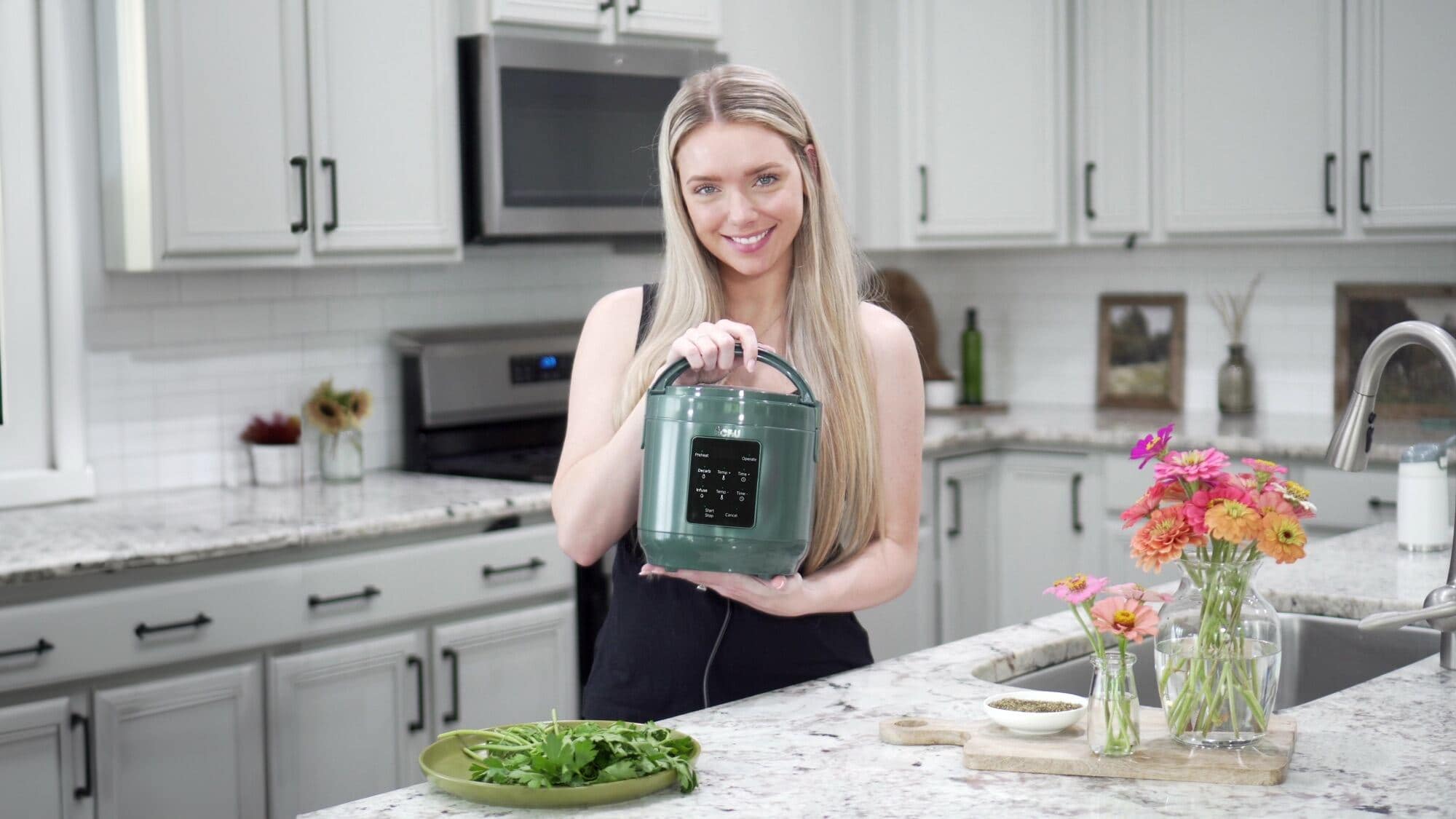 Host holding the ÉCRU 3oz decarboxylator in a bright home kitchen