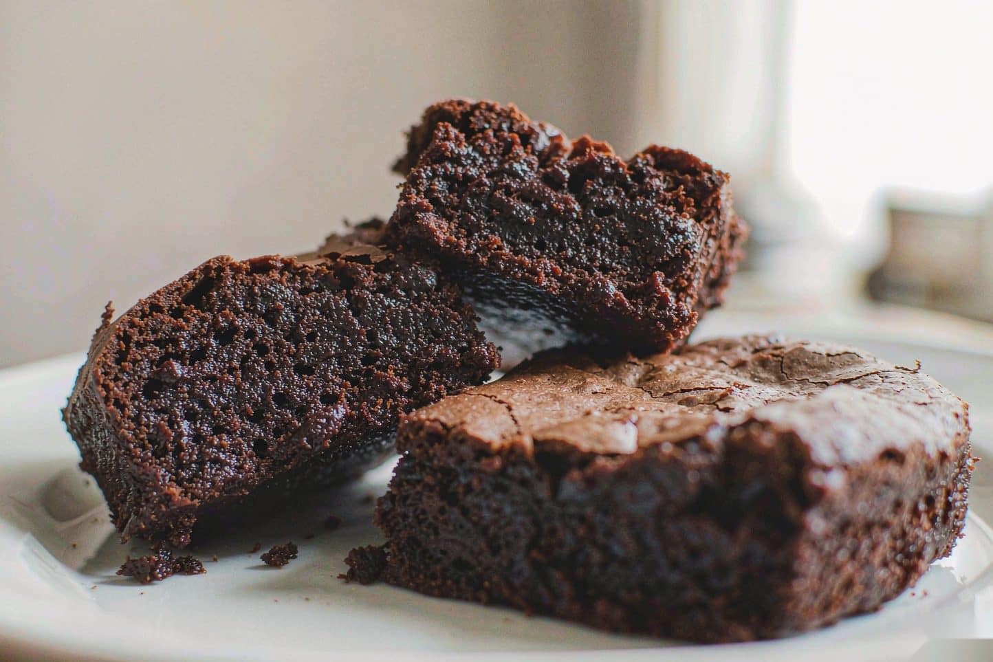 Three cut brownies stacked on a plate, one turned to show its fudgy crumb