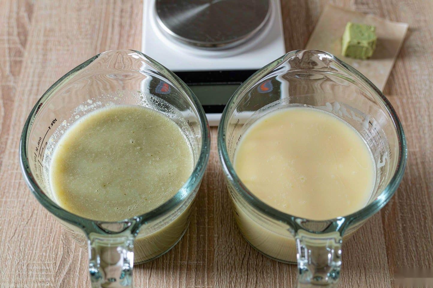 Cannabutter and regular butter in two identical glass measuring cups beside a kitchen scale