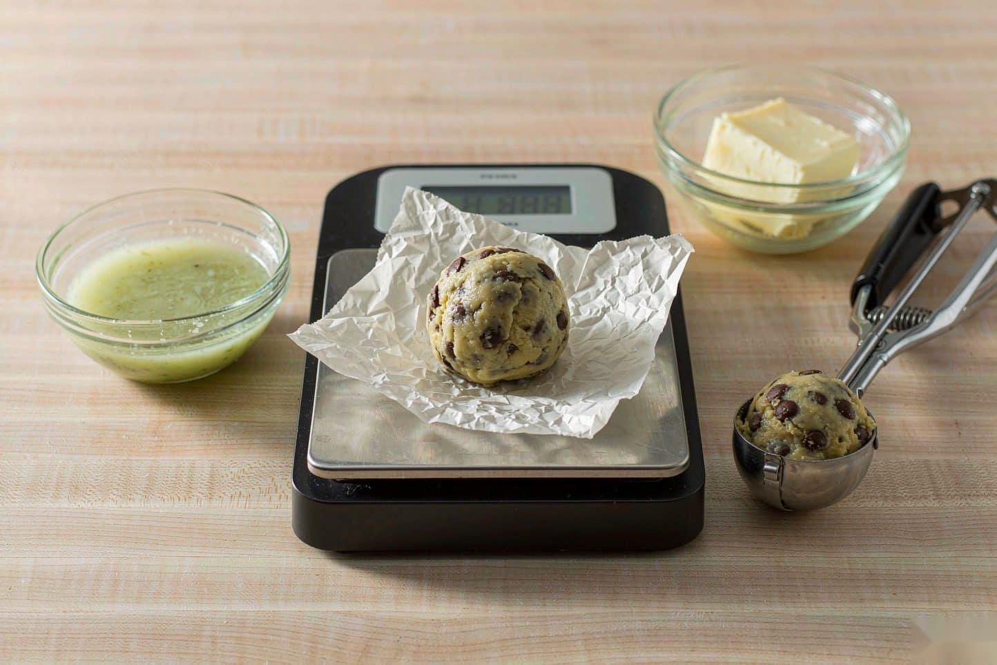 A bowl of cannabutter and a bowl of regular butter either side of a scale and cookie scoop