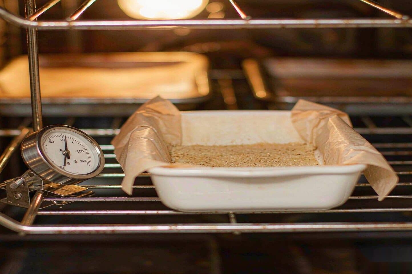 Thin layer of kief on parchment in an oven with an oven thermometer